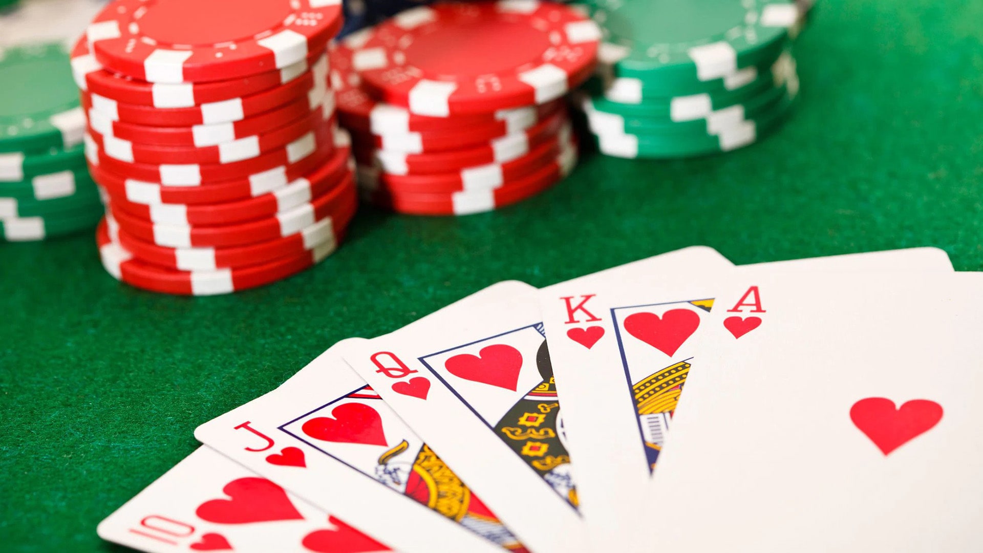 A close-up view of a poker game in action, showcasing playing cards and chips on a classic green table.