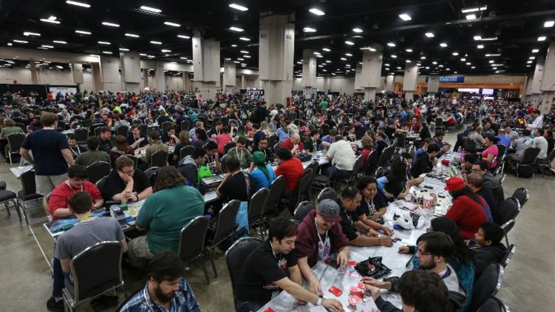 A bustling tabletop gaming convention with attendees engaging in various board games, showcasing the community and excitement of these events.
